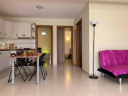 a kitchen and living room with a table and a pink couch at Sea melodies apartment 1 in Koroni