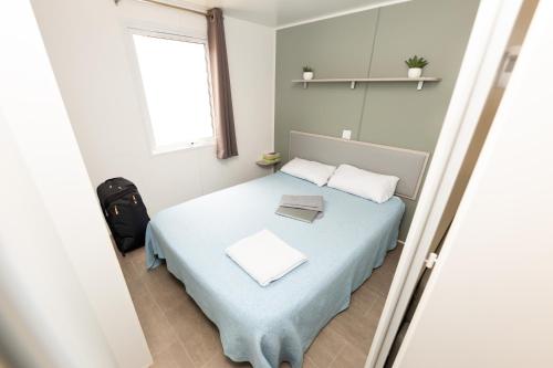 a bedroom with a bed with a blue blanket and a window at Camping Bellsol Pets in Pineda de Mar