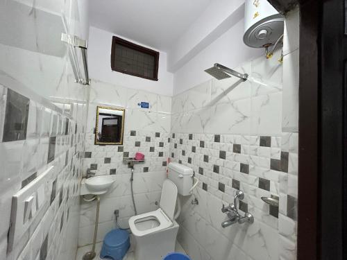 a white bathroom with a toilet and a sink at Ashish Guest House, Udaipole in Udaipur