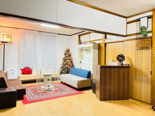 una sala de estar con un árbol de Navidad y un sofá en 悠客山荘 en Yuzawa