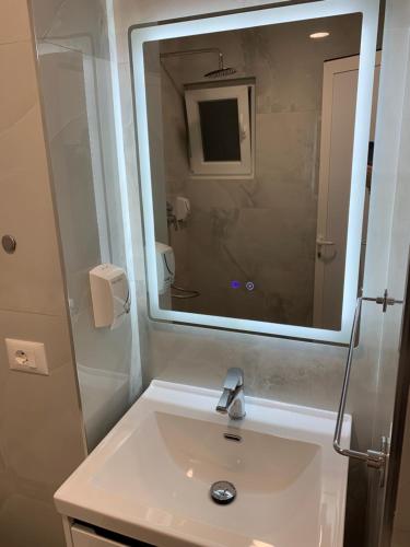 baño con lavabo y espejo grande en Tirana Apartment, en Tirana