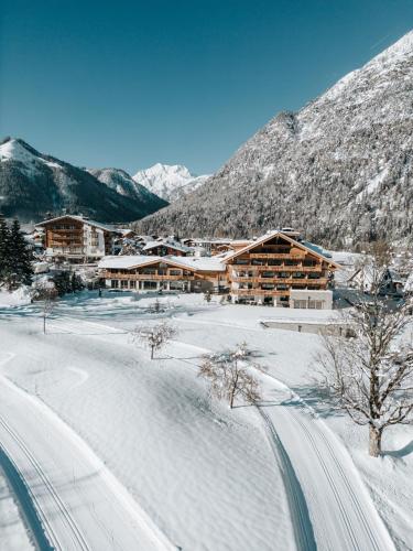 a ski lodge in the mountains with snow on the ground at NOVA Moments Boutique Hotel in Pertisau