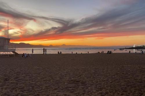 eine Gruppe von Menschen am Strand bei Sonnenuntergang in der Unterkunft Oasis in Las Palmas de Gran Canaria