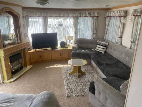 a living room with a couch and a television at Caravan F8 Aberystwyth Holiday Village in Aberystwyth