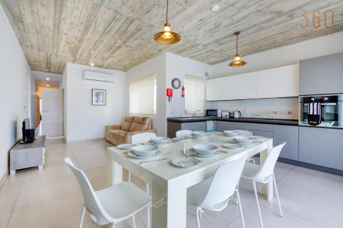 cocina y comedor con mesa blanca y sillas en A fully equipped 3BR penthouse with large terrace by 360 Estates, en Il-Gżira