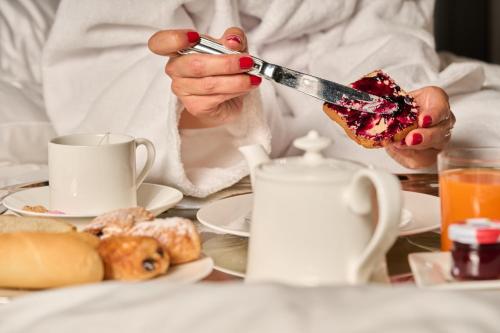 Eine Person, die ein Stück Essen mit Gabel und Messer hält. in der Unterkunft Loly Boutique Hotel Roma in Rom