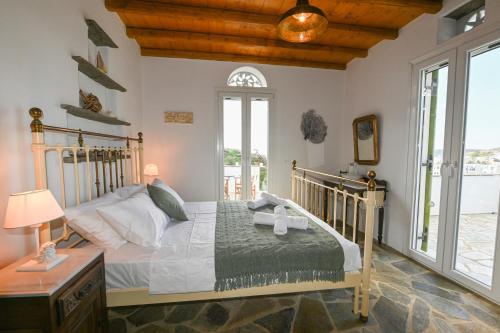 um quarto com uma cama com uma moldura de madeira e janelas em White Home Pigeons em Kionia