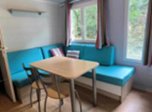 uma sala de estar com uma mesa e um sofá azul em Mobil-Home Camping naturiste em Méjannes-le-Clap