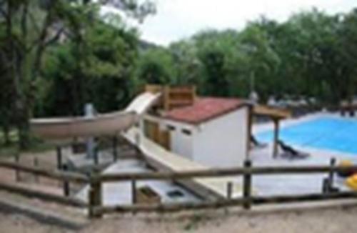 una piscina con un pequeño edificio junto a una piscina en Mobil-Home Camping naturiste, en Méjannes-le-Clap