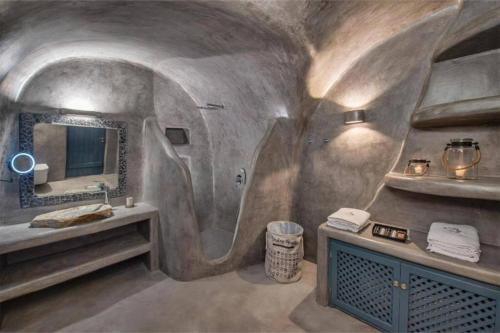 a bathroom in a cave with a sink and a mirror at Alexis Place in Oia