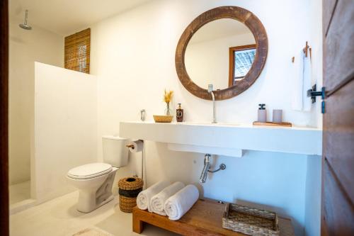 a bathroom with a sink and a toilet and a mirror at Villa Kandui Boutique Hotel e Beach Lounge in Barra Grande