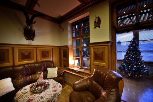 a living room with a christmas tree and leather furniture at Vila Aurora - Vysoke Tatry in Mlynčeky