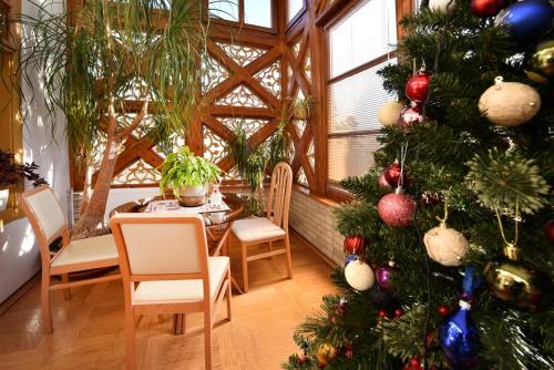 a christmas tree in a room with a table and chairs at Vila Aurora - Vysoke Tatry in Mlynčeky