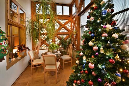 a christmas tree in a room with a table and chairs at Vila Aurora - Vysoke Tatry in Mlynčeky