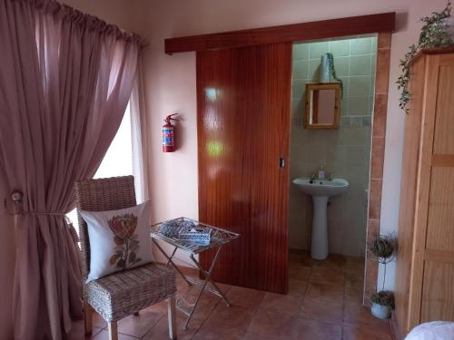 a bathroom with a door and a chair and a sink at Acacia Gastehuis in Kathu