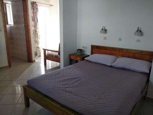 a bedroom with a large bed with a wooden headboard at Ton Mari Apartments in Palaiochora