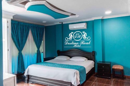 een slaapkamer met een bed met een blauwe muur bij Destino real hotel in Arauca