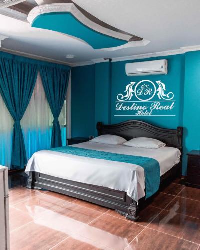 a bedroom with a bed with a blue wall at Destino real hotel in Arauca