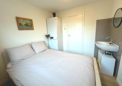 ein Schlafzimmer mit einem weißen Bett und einem Waschbecken in der Unterkunft Helmpol in Buren
