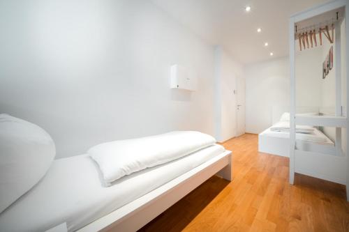 uma cama branca num quarto com piso em madeira em CityFlat 38 Schladming by globboard em Schladming