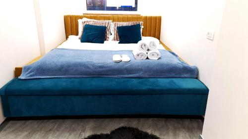 1 dormitorio con 1 cama con sábanas azules y toallas en Mogosoaia High Living Apartment, en Chitila
