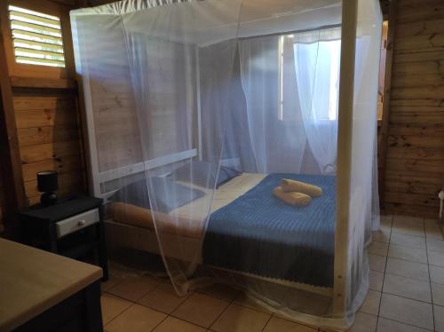 sypialnia z łóżkiem z baldachimem i 2 żółtymi poduszkami w obiekcie Le tri Haut de Bellevue - Bungalow Manguier w mieście Pointe-Noire