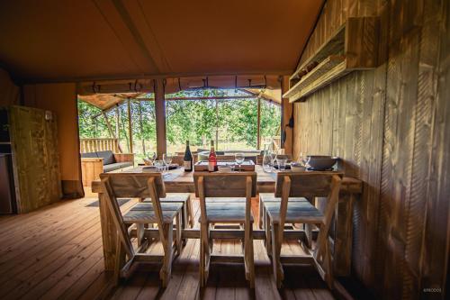 une salle à manger avec une table et des chaises en bois dans l'établissement Tente lodge insolite Jacuzzi privatif en pleine nature, à Thiel-sur-Acolin