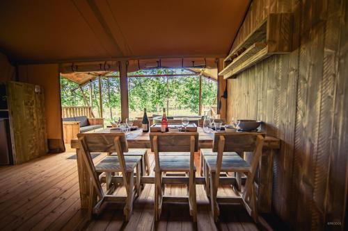 a dining room with a wooden table and chairs at Tente lodge Jacuzzi privatif en pleine nature in Thiel-sur-Acolin