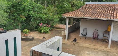 un chien debout devant une petite maison dans l'établissement Chácara Cuesta Machado, à Botucatu