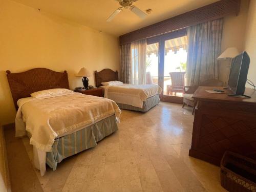 Royal Arabian Stylish Chalets in Four Seasons Resort - By Royal Vacations في شرم الشيخ: غرفة نوم بسريرين وتلفزيون فيها