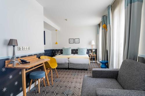 une chambre d'hôtel avec un lit et un canapé dans l'établissement Hôtel Augustin - Astotel, à Paris