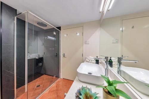 ein Bad mit einer Dusche, einem Waschbecken und einem WC in der Unterkunft Resort Style Escape King Bed Pool Balcony in Darwin