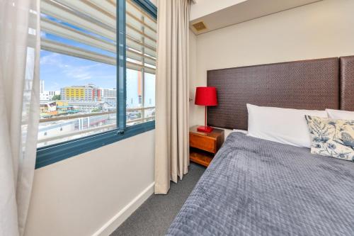 ein Schlafzimmer mit einem Bett und einem großen Fenster in der Unterkunft Resort Style Escape King Bed Pool Balcony in Darwin