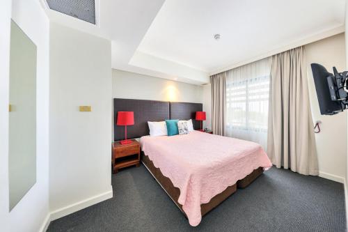 a bedroom with a pink bed and a window at Resort Style City View King Bed Pool Balcony in Darwin