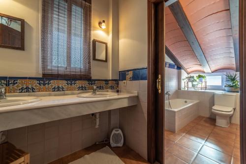 uma casa de banho com 2 lavatórios, uma banheira e um WC. em Casa El Oasis del Lago Alojamiento Rural em Córdoba