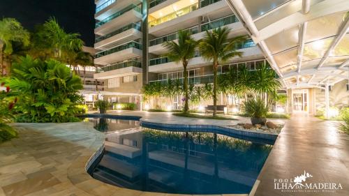 an office building with a pool and palm trees at Pool Ilha da Madeira Resort in Riviera de São Lourenço