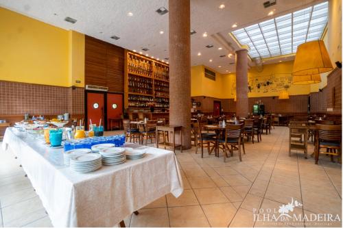 un restaurante con una mesa con platos en Pool Ilha da Madeira Resort, en Riviera de São Lourenço