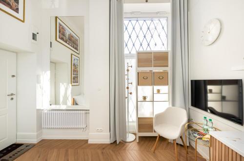 a white apartment with a window and a white chair at WILCZA Abdank City Center Studio in Warsaw