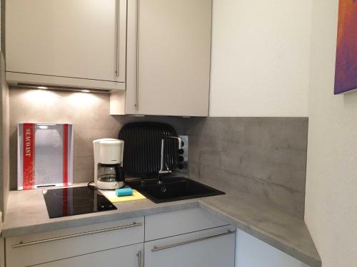 eine Küche mit weißen Schränken und einer Kaffeemaschine auf der Theke in der Unterkunft Rosenhus 2 in Horumersiel