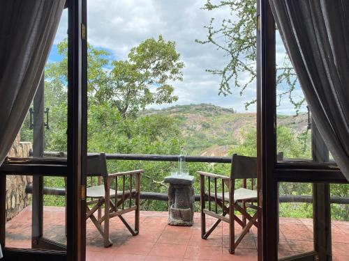 a view from a room with two chairs and a table at Big Cave Camp in Matopos