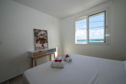 a bedroom with a white bed with a window at ILET TURQUOISE in Le Gosier