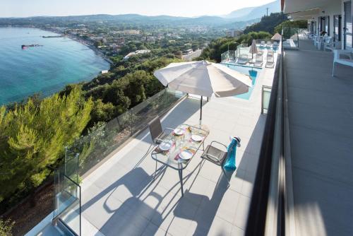 a balcony with an umbrella and chairs and the water at Cp 5 Bedrooms NL Villas Lucas Clara Pyrgi in Pyrgi