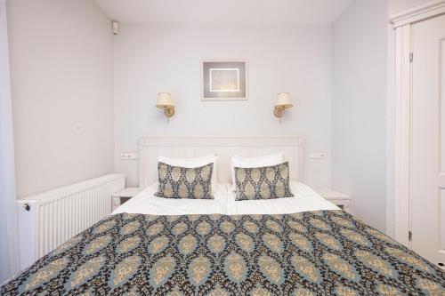 a white bedroom with a large bed with two pillows at Art Hotel in Druskininkai