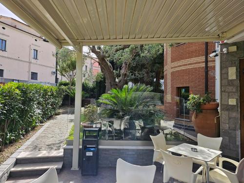 eine Terrasse mit weißen Stühlen, einem Tisch und einem Gebäude in der Unterkunft Hotel Sirio in Rotonda
