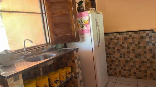 eine Küche mit einem weißen Kühlschrank und einer Spüle in der Unterkunft Pousada Recanto do Galo in Santa Cruz Cabrália