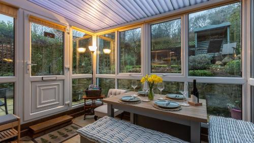 a conservatory with a table and a bunch of windows at Picturesque Stone Cottage in the Heart of North Yorkshire Village in York