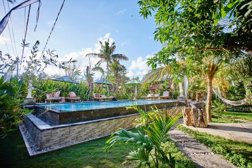 una piscina en un patio con sillas y árboles en Taos House Lembongan By DeWizZ Management, en Nusa Lembongan