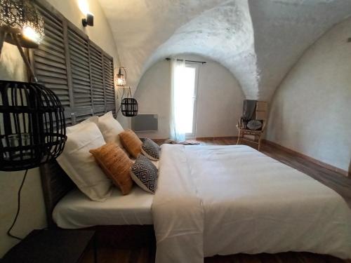 une chambre avec un grand lit blanc avec des oreillers dans l'établissement Bastide la Bohême, à Ollioules