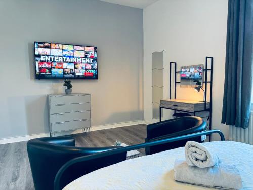 a bedroom with a bed and two chairs and a tv at Jacksons Apartment, Close to Tynemouth in Tynemouth