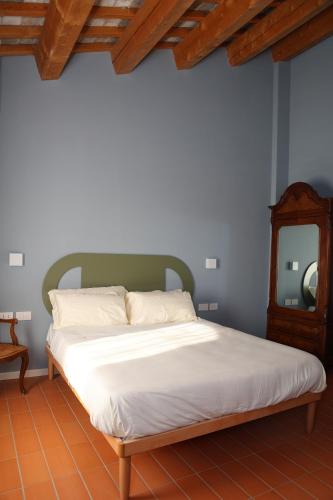 1 cama con sábanas blancas y cabecero de madera en Locanda Lingua, en Rímini